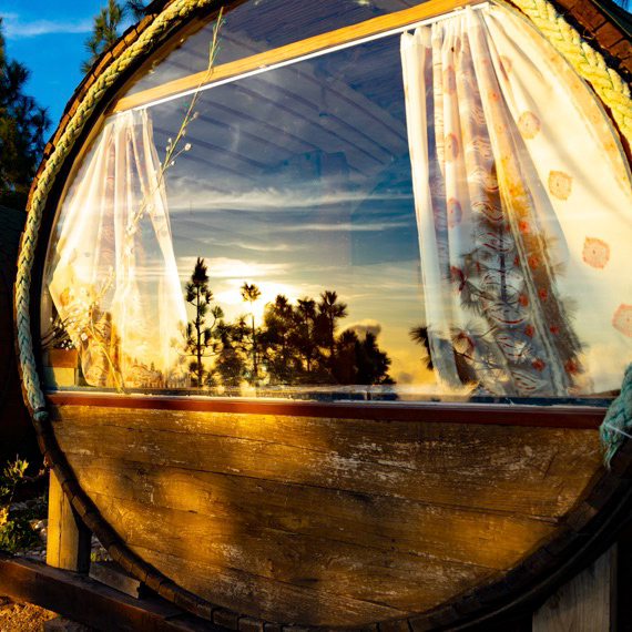 Romantyczny domek w kształcie beczki z tarasem i widokiem na las oraz ocean.